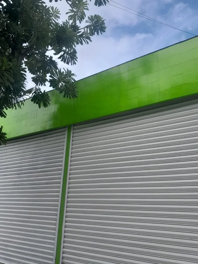 Fachada de local comercial terminada en color verde con cortinas metálicas